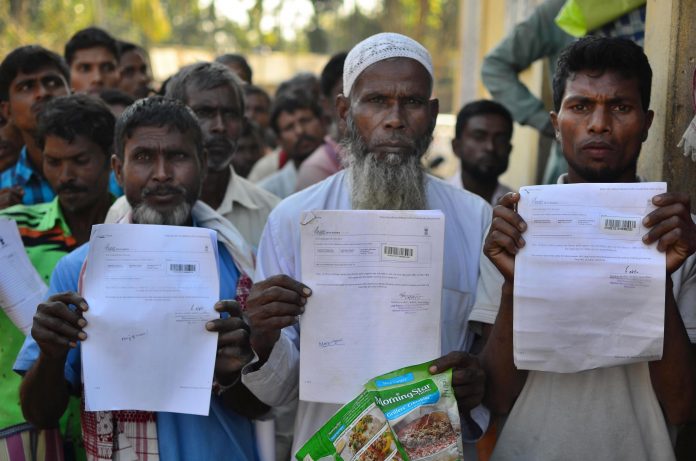 People show their acknowledgment receipts after checking in their names in a draft for NRC. Credit: PTI