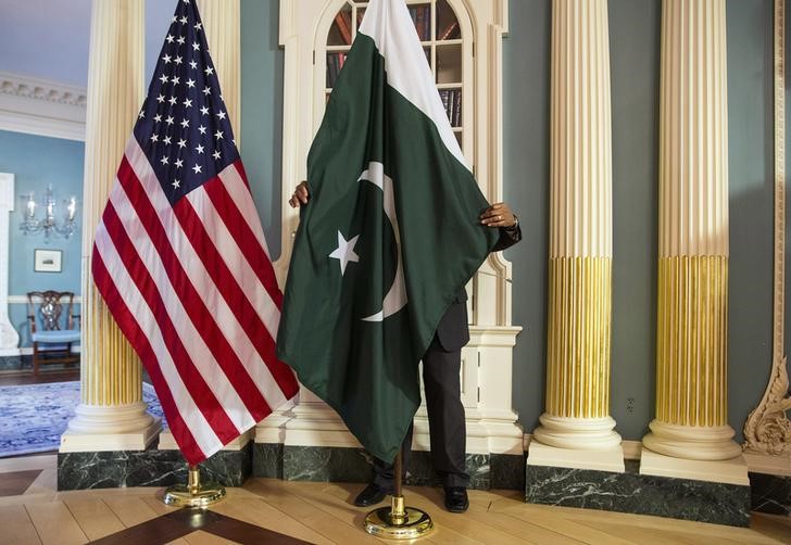 A State Department contractor adjust a Pakistan national flag before a meeting between US Secretary of State John Kerry and Pakistan's Interior Minister Chaudhry Nisar Ali Khan on the sidelines of the White House Summit on Countering Violent Extremism at the State Department in Washington February 19, 2015. Credit: Reuters/Joshua Roberts