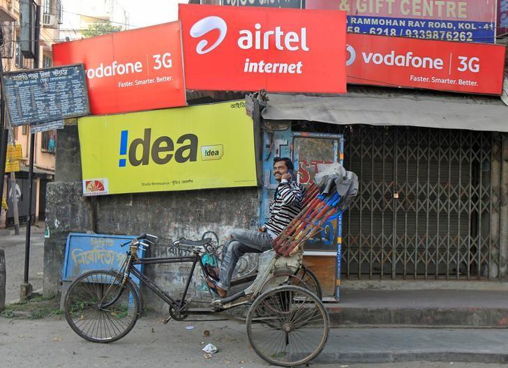 A rickshaw puller speaks on his mobile phone as he waits for customers in front of advertisement billboards belonging to telecom companies in Kolkata, February 3, 2014. Credit: Reuters/Rupak De Chowdhuri/Files