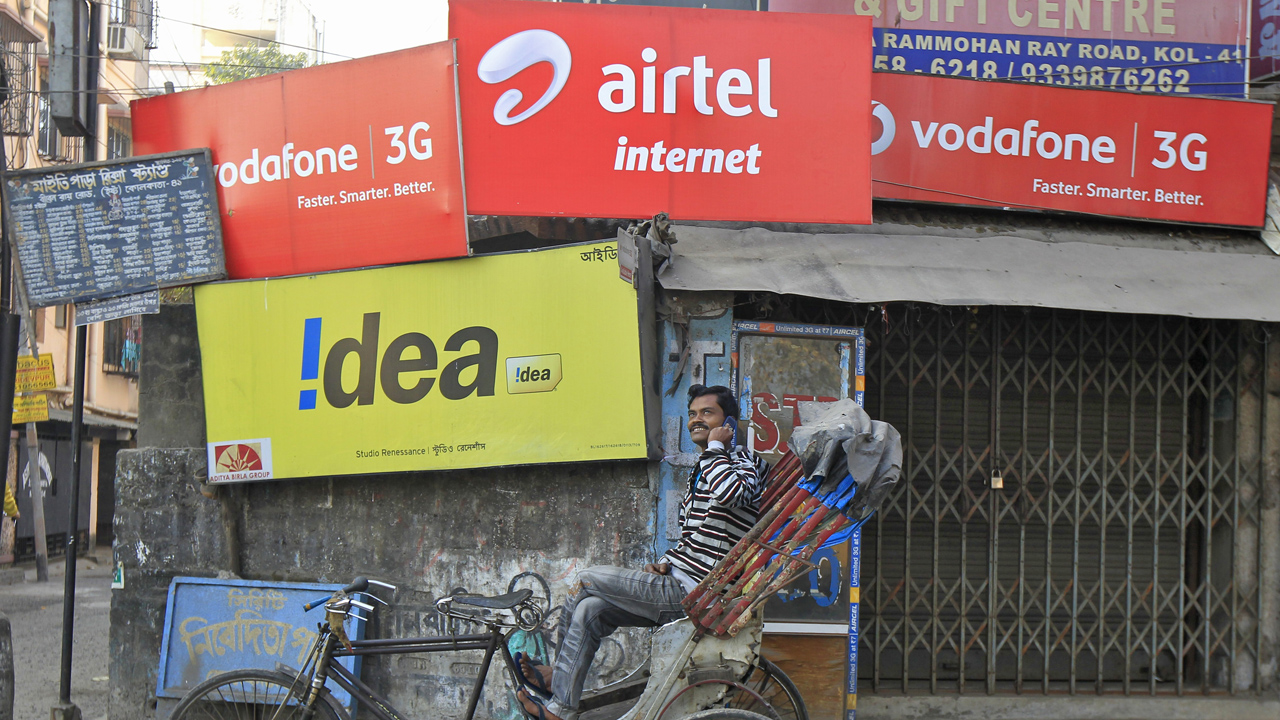 A rickshaw puller speaks on his mobile phone as he waits for customers in front of advertisement billboards belonging to telecom companies in Kolkata February 3, 2014. Credit: Reuters/Rupak De Chowdhuri