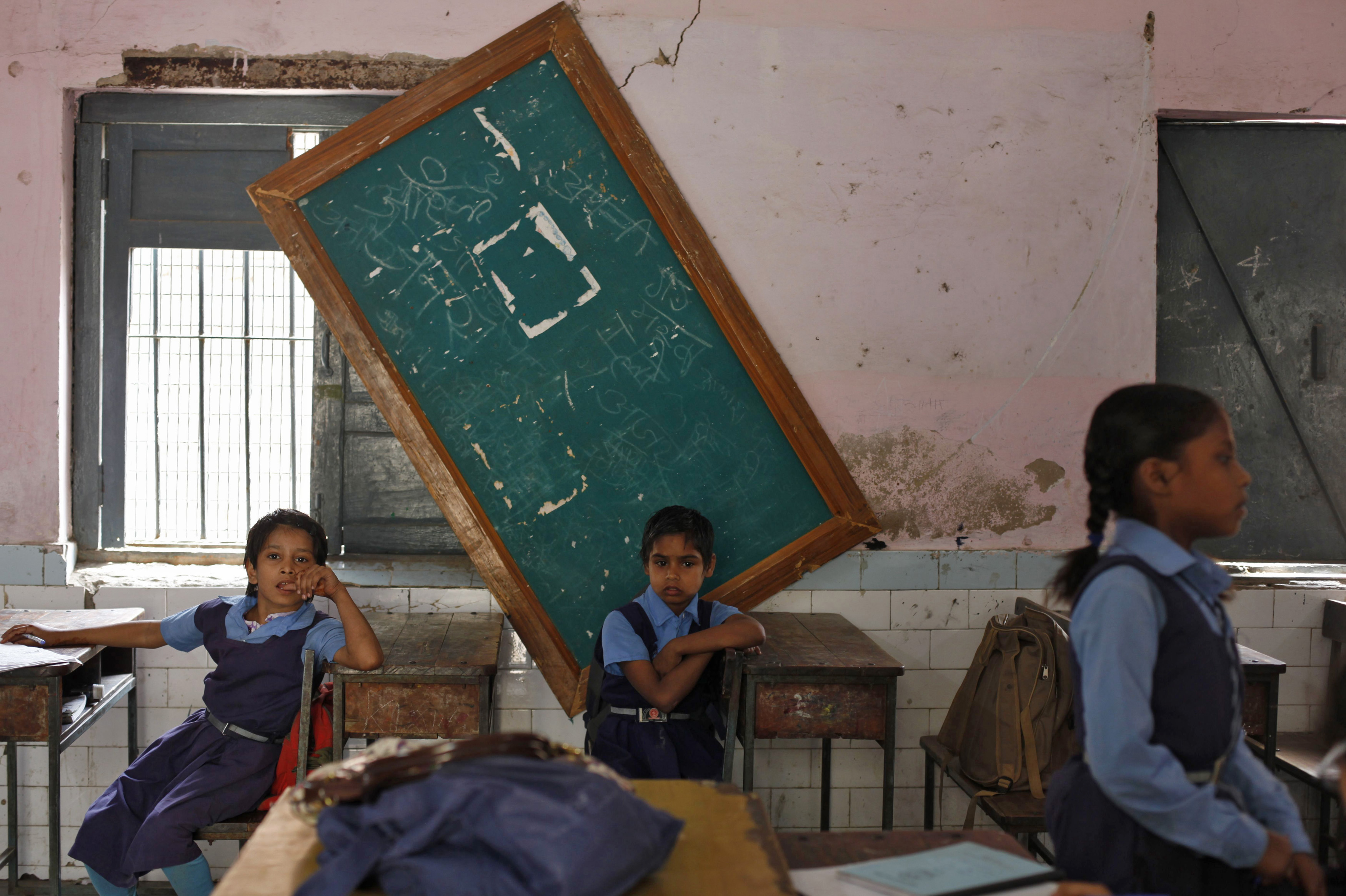 Schoolgirls sit inside their classroom before collecting their free mid-day meals, being distributed by a government-run primary school, in New Delhi May 8, 2013. India may soon pass a new law to give millions more people cheap food, fulfilling an election promise of the ruling Congress party that could cost about $23 billion a year and take a third of annual grain production. The National Food Security Bill, which aims to feed 70 percent of the population, could widen India's already swollen budget deficit next year, increasing the risk to its coveted investment-grade status.