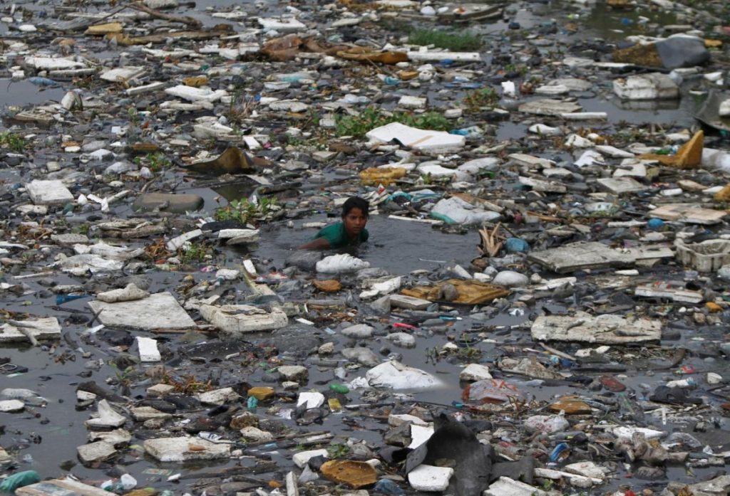 A boy searches for fish in the polluted sea backwaters near marina beach in the southern Indian city of Chennai July 3, 2013. Credit: Reuters/Babu/Files