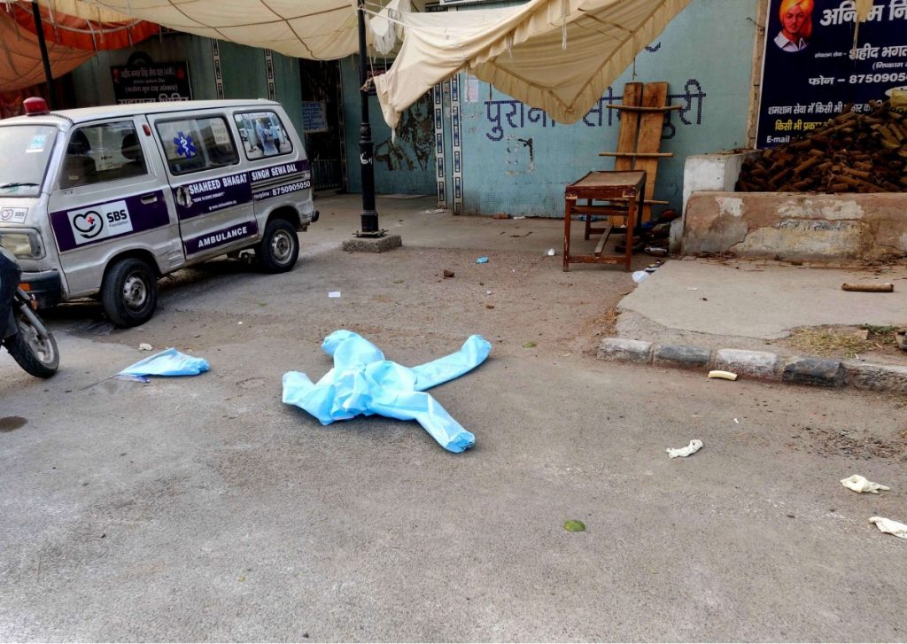Outside the Seemapuri Crematorium, a PPE kit blows on the street.