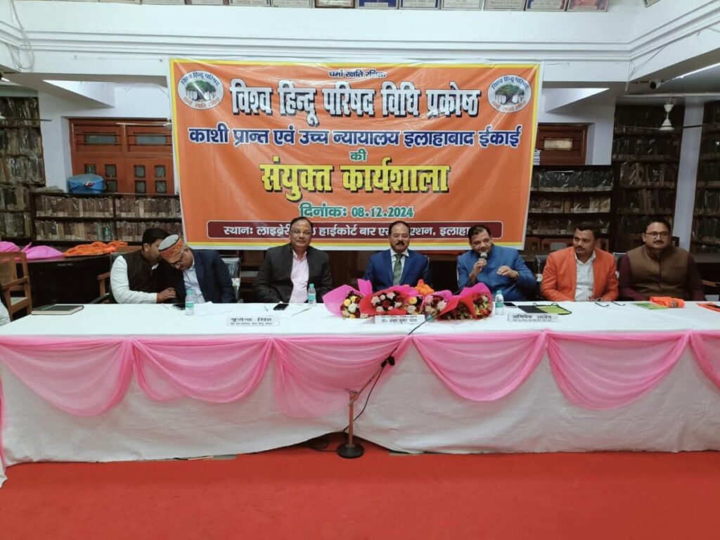 Men sit at a table for a discussion. A banner behind them announces it is a VHP event.