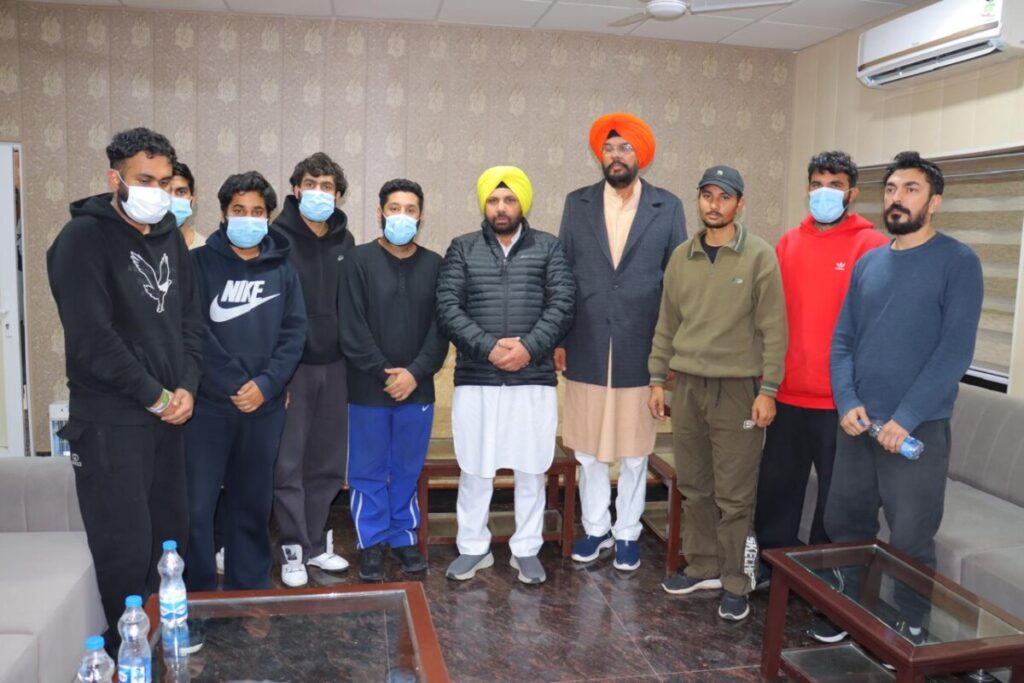 Punjab's NRI affairs minister stands next to deportees at the Amritsar airport.