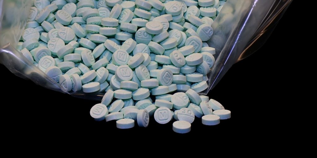 Opioid pills overflow out of a bag.