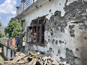 A resident looks out of his shattered windows at the impacts of artillery firing on his home in a village on the India-Pakistan border on May 9 in Poonch district, Jammu.