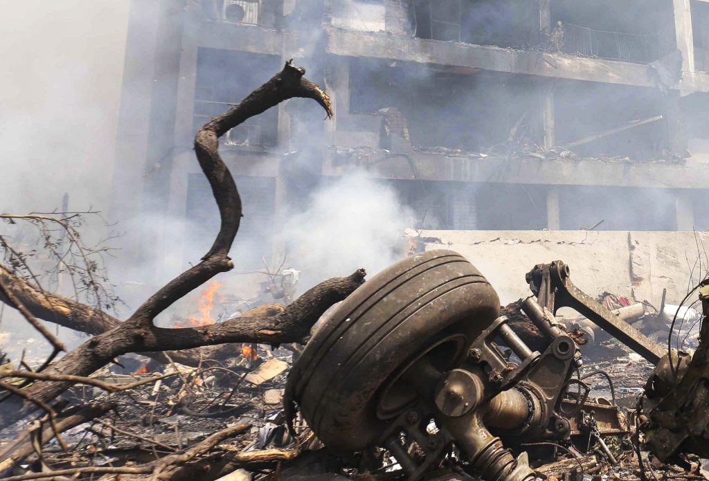 A wheel from Air India flight 171 lies amid other debris as smoke billows from the site of the crash.