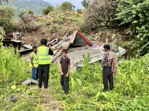 A residential house is seen buried in the ground as rescue workers film the aftermath in Kalban village of Poonch (Photo: Nazim Ali Manhas).