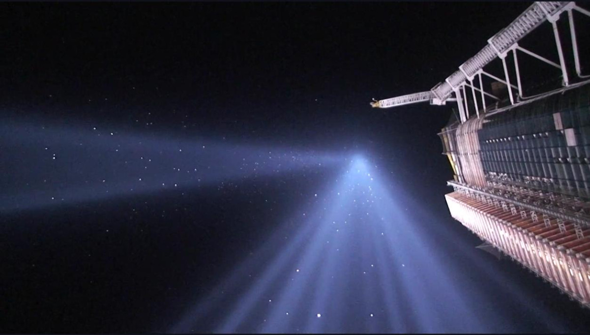 Screenshot from a youtube video uploaded by Benjamin Van Doren: During New York’s 9/11 Tribute in Light, thousands of migrating songbirds become disoriented by the powerful beams, circling within them for hours. In this image, the birds appear as illuminated streaks flying through the lights of high intensity.