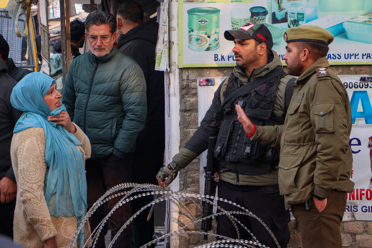 A police officer stops a woman near a barricaded area in Srinagar where a blast happened in a police station Friday noght.