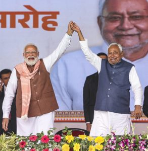 Prime Minister Narendra Modi raises the hand of Bihar Chief Minister Nitish Kumar after the swearing-in ceremony at Gandhi Maidan, in Patna.