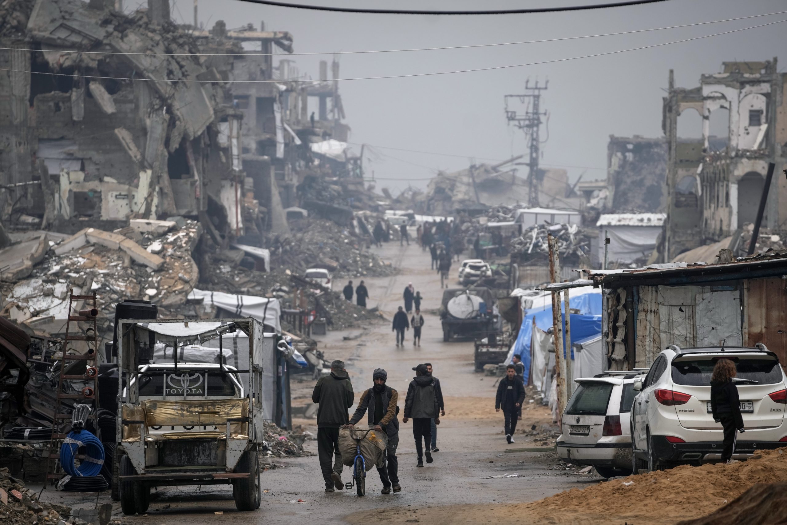  Palestinians walk along a street lined with war-damaged buildings in the rain in Gaza City, Monday, December 15, 2025. Photo: AP/PTI