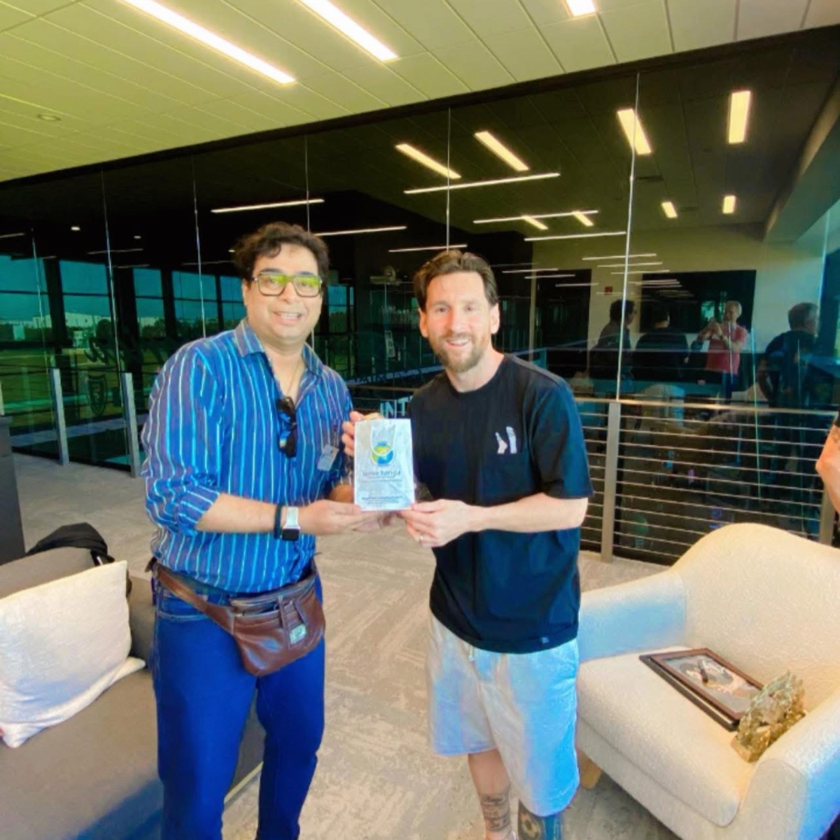 Satadru Dutta giving a book to Lionel Messi.