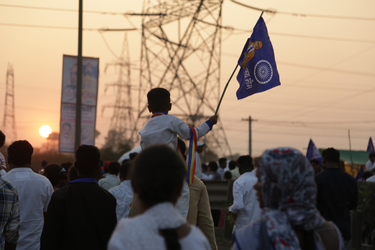 A young child takes part in the Bhima Koregaon gathering, holding an Ambedkarite flag in the sky. 