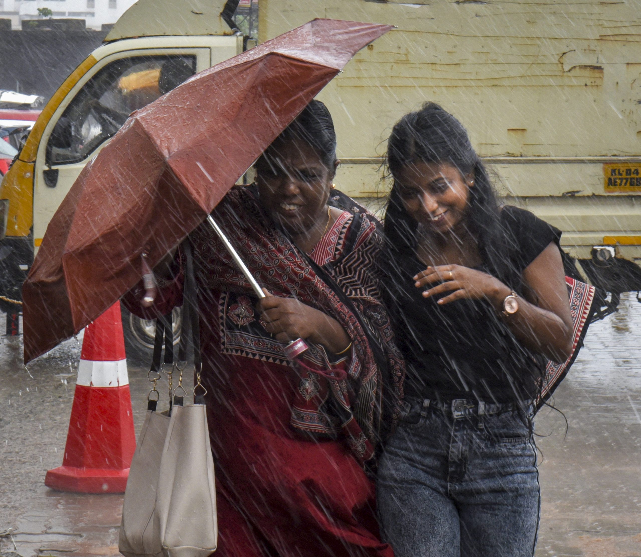 Women cover themselves amid rainfall as the southwest monsoon set over Kerala according to the India Meteorological Department (IMD), in Kochi. Photo: PTI